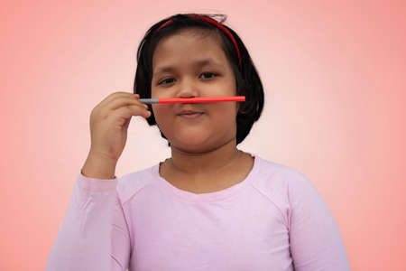 girl using a pencil as pretend moustache, on a color backgroundの写真素材