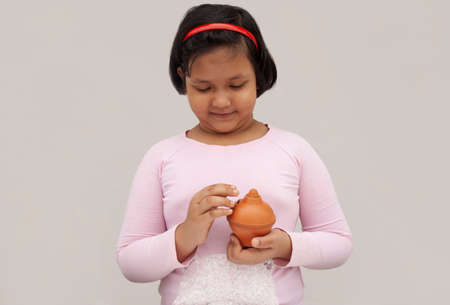 Young child putting coins into piggy bankの写真素材