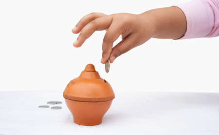 Little Girl putting coin into piggy bank, close-upの写真素材