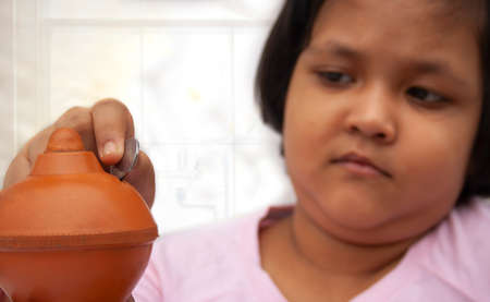 Young child putting coins into piggy bankの写真素材