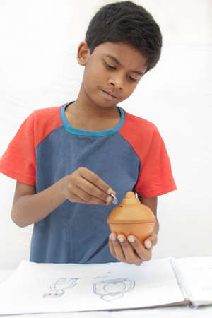Close-up Boy putting coins into piggy bankの写真素材