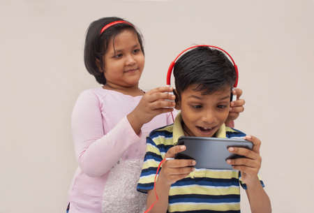 indian kids listening to the music of his smartphone with headphonesの写真素材