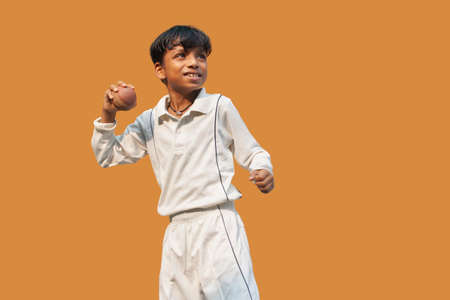 A boy in cricket uniform standing Holding a ballの写真素材
