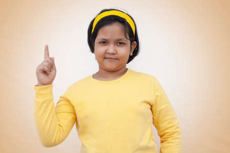 Portrait Of Girl Pointing While Standing Against Color Backgroundの写真素材