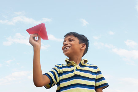 Boy playing with a paper plane and smilingの写真素材