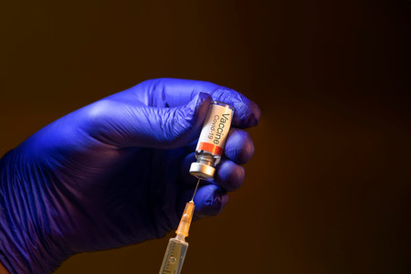 Hand with blue glove using syringe to draw Covid-19 Vaccineの写真素材