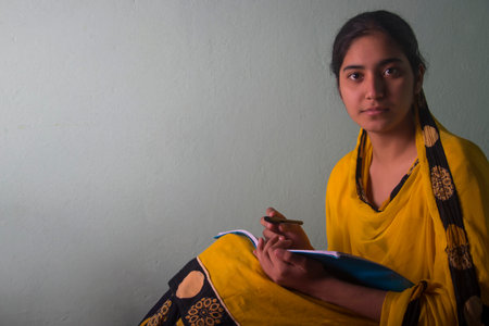 Indian teenage girl writing in notebook at homeの写真素材
