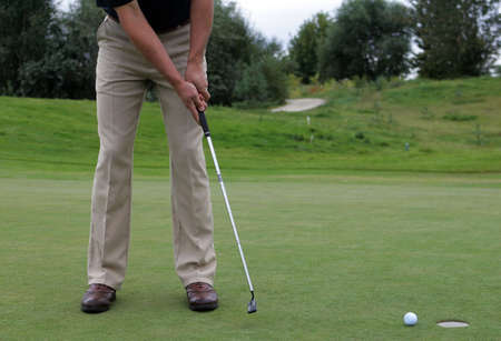 Golf player hotting ball into a holeの写真素材
