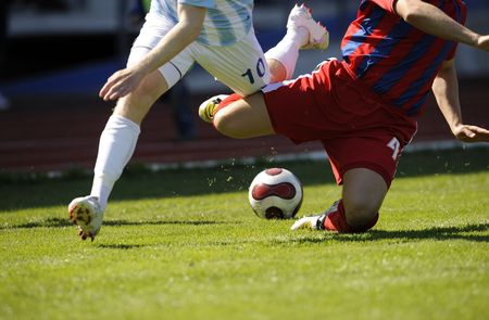 two male soccer players is fighting for the ballの写真素材