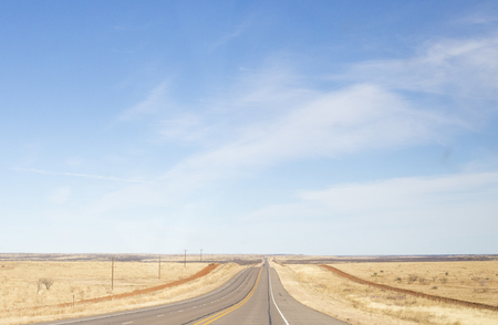 A long stretch of road in a dry climent with a beautiful blue skyの写真素材