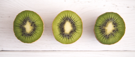 Sliced Kiwi Fruit on a White Wood Table in a Bright Kitchenの写真素材
