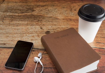 Physical Bible and a Smart Phone with Earphones on a Wood Tableの写真素材