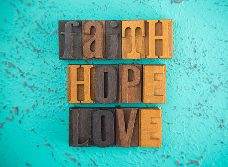 Faith Hope and Love  Spelled in Wooden Type Set Block Letters on a Turquoise Backgroundの写真素材