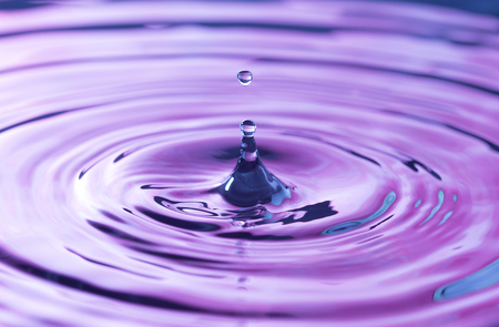 SImple Water Droplets into a Pool of Water with a Purple Reflectionの写真素材