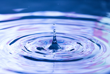SImple Water Droplets into a Pool of Water with a Red and Blue Reflectionの写真素材