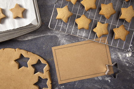A Batch of Gingerbread Stars Being Made on a Dark Surface with a Blank Recipe Cardの写真素材