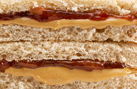 A Background of a Classic Peanut Butter and Strawberry Jelly Sandwich on Wheat Breadの写真素材