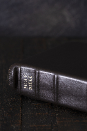 A Bible on a Wooden Table in a Dark Environmentの写真素材