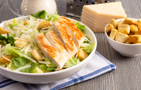 Fresh Chicken Caesar Salad on a Wooden Kitchen Tableの写真素材