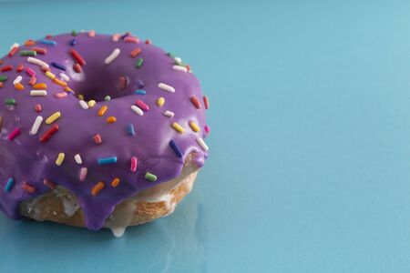 A Purple Glazed Donut with Rainbow Sprinkles on Top