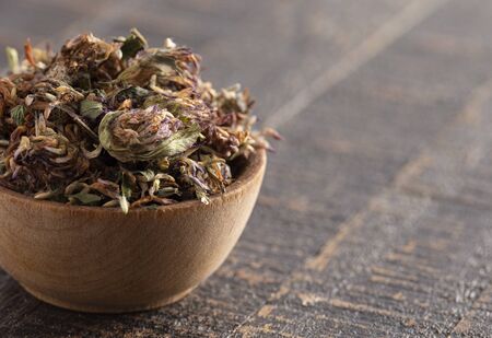 Dried Red Clover Flowers and Leaves on a Rustic Wooden Tableの写真素材