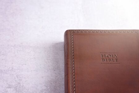 Brown Leather Holy Bible on a White and Gray Concrete Surfaceの写真素材