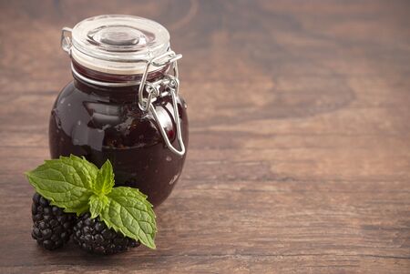 A Jar of Homemade Blackberry Jam on a Rustic Wooden Table