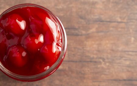 A Glass Canning Jar Filled with Cherry Pie Filling on a Wooden Tableの写真素材