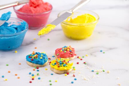 Cookies Decorated with Bright Primary Colored Frosting with Rainbow Sprinklesの写真素材