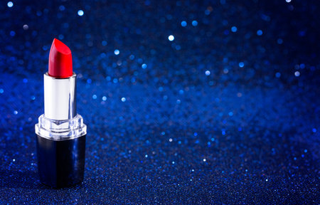 A Tube of Classic Bright Red Lipstick on a Blue Glittery Backgroundの写真素材