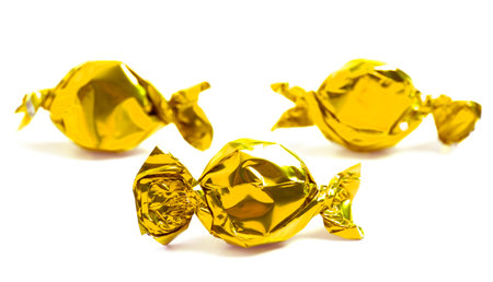 Three Golden Wrapped Candy Isolated on a White Backgroundの写真素材