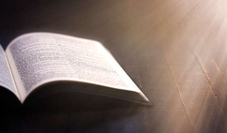 Bible Open on a Wooden Table with Pages Blowing Open