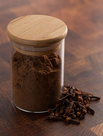 Ground and Whole Cloves on a Beautiful Wooden Butcher Blockの写真素材