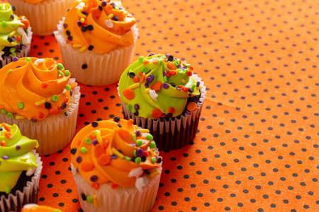 Halloween Themed Cupcakes with Sprinkles on an Orange and Black Tableの写真素材