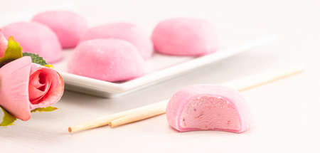 A Pink Mochi Ice Cream with a Rose Flower on a White Tableの写真素材