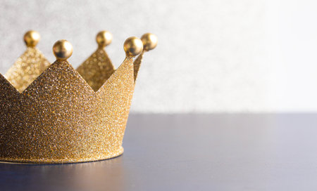 A Classic Golden Crown on a Blue Table with Lightの写真素材