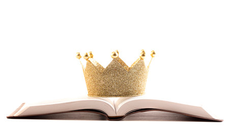 A Golden Crown on a Holy Bible Isolated on a White Backgroundの写真素材