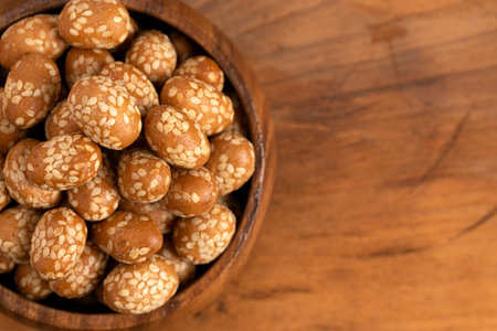 A Bowl of Crunchy Asian Sesame Peanuts with Soy Sauce on a Wooden Counterの写真素材