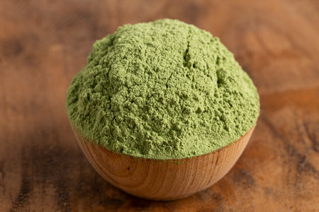 Bowl of Green Kale Powder on a Wooden Counter Topの写真素材