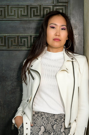 A beautiful cheeky young woman in front of an old huge door.