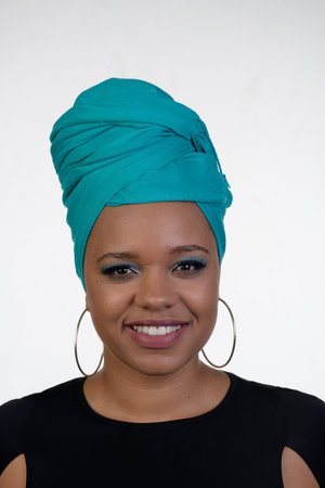 A very pretty young African American woman with a turquoise turban on her head with a white background.の写真素材