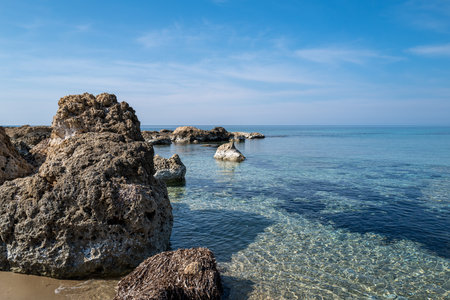 On a beautiful, quiet stretch of beach on an island in the Mediterranean Sea, large erratic boulders lie scattered about. The water of the sea is very clear and inviting for a swimの写真素材