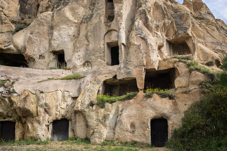 Rock-cut dwellings in Cappadocia, Turkey. Carved into volcanic rock, these structures provided shelter and defense for early inhabitants, showing human adaptation.の写真素材
