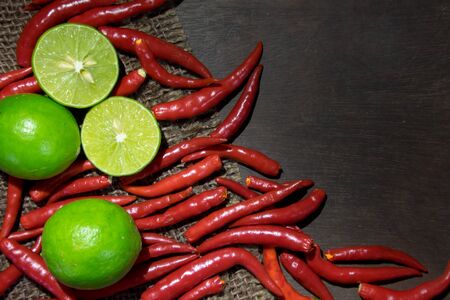 Limes and Chillies on dark wood backgroundの写真素材