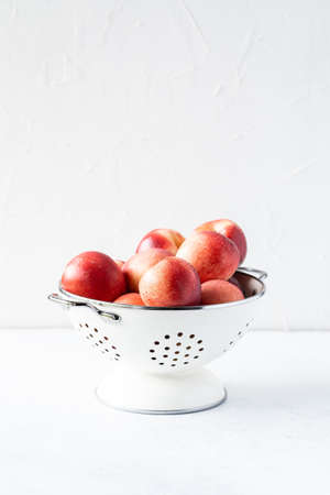 Fresh peaches and nectarines for a delicious Breakfast in a white iron bowl on a white background. The concept of delicious and healthy food. Copy space.の写真素材