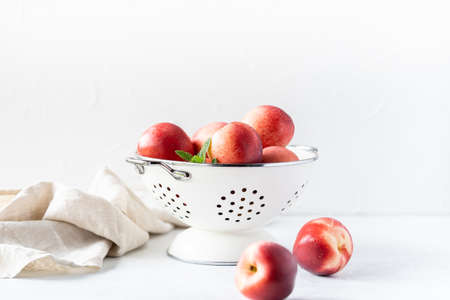 Fresh peaches and nectarines for a delicious Breakfast in a white iron bowl on a white background. The concept of delicious and healthy food. Copy space.の写真素材