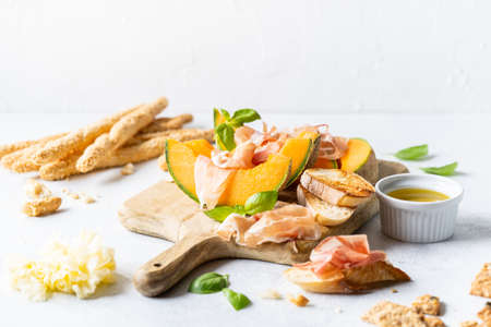 Fresh melon with prosciutto and basil. Antipasti, Italian food. Top view on white stone table with copy space for your textの写真素材