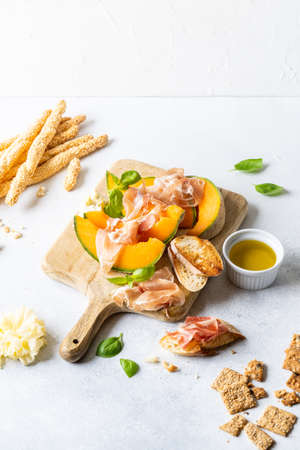 Fresh melon with prosciutto and basil. Antipasti, Italian food. Top view on white stone table with copy space for your textの写真素材