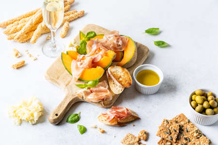 Fresh melon with prosciutto and basil. Antipasti, Italian food. Top view on white stone table with copy space for your textの写真素材