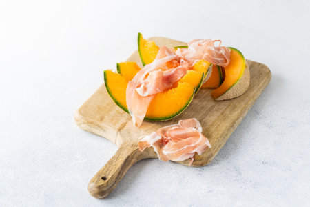 Fresh melon with prosciutto and basil. Antipasti, Italian food. Top view on white stone table with copy space for your textの写真素材